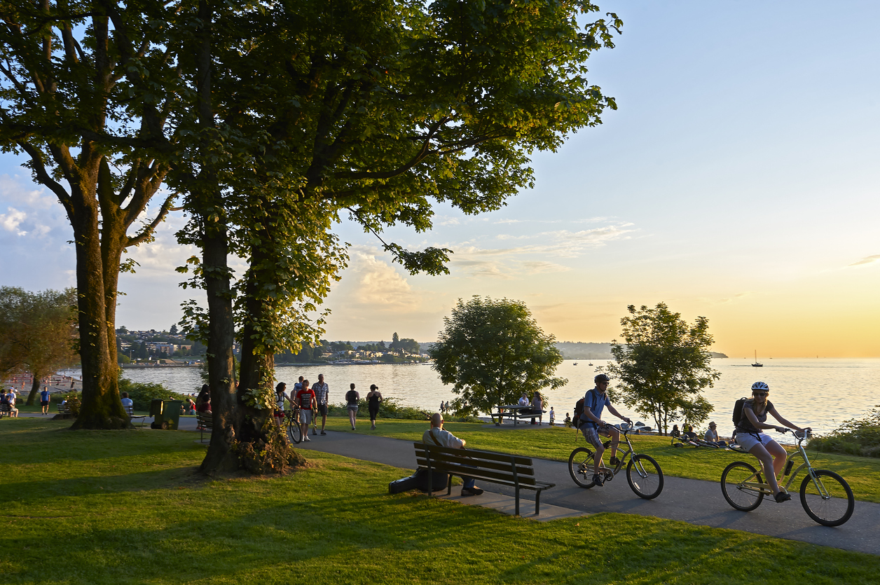 public park at sunset with people sitting on benches and riding bikes