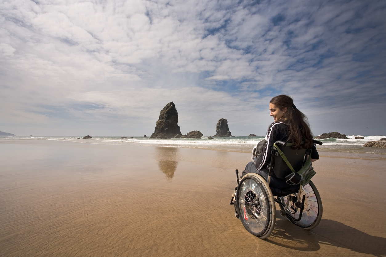 traveler in a wheelchair at haystack rock in cannon beach, oregon