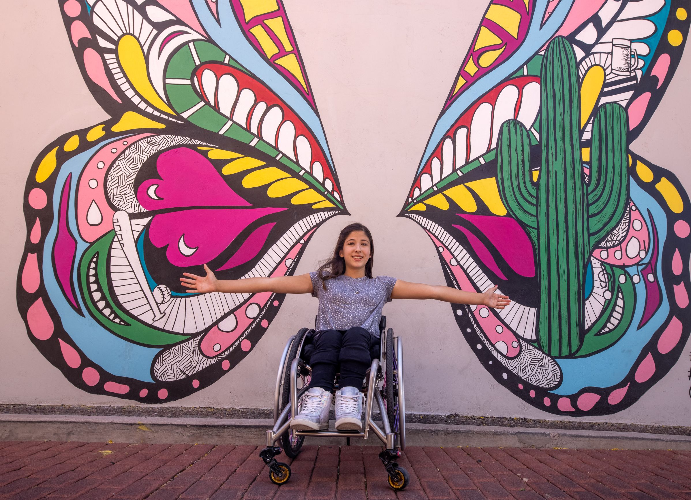 girl in a wheelchair in front of a butterfly mural