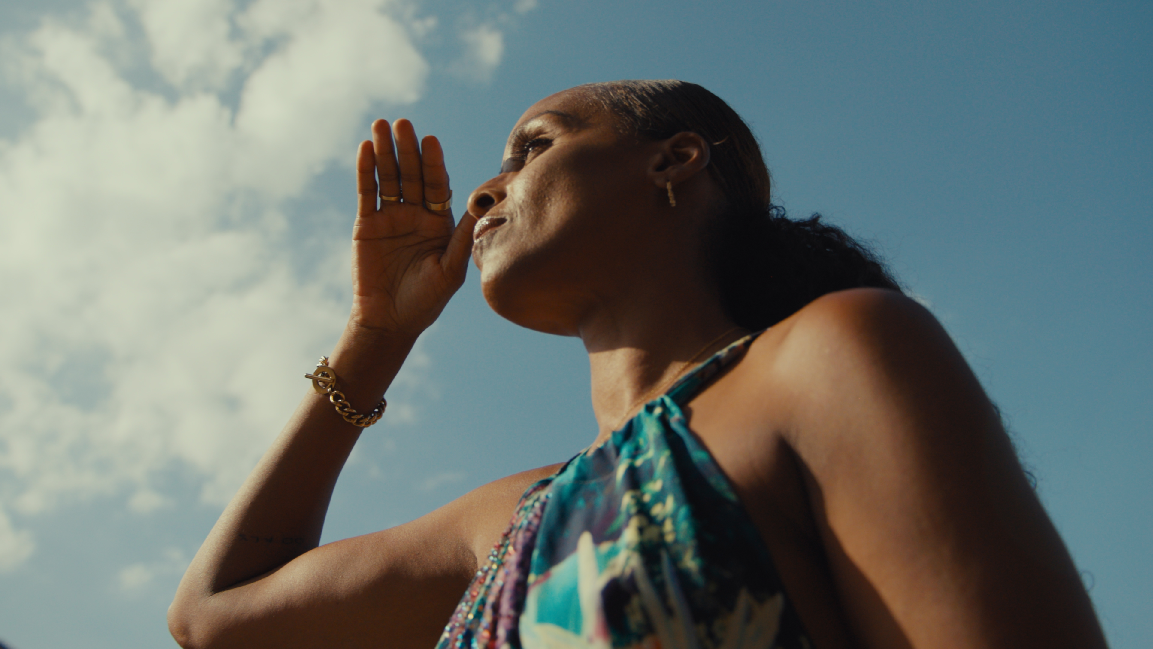 woman with her hand in front of her face with the sky in the background