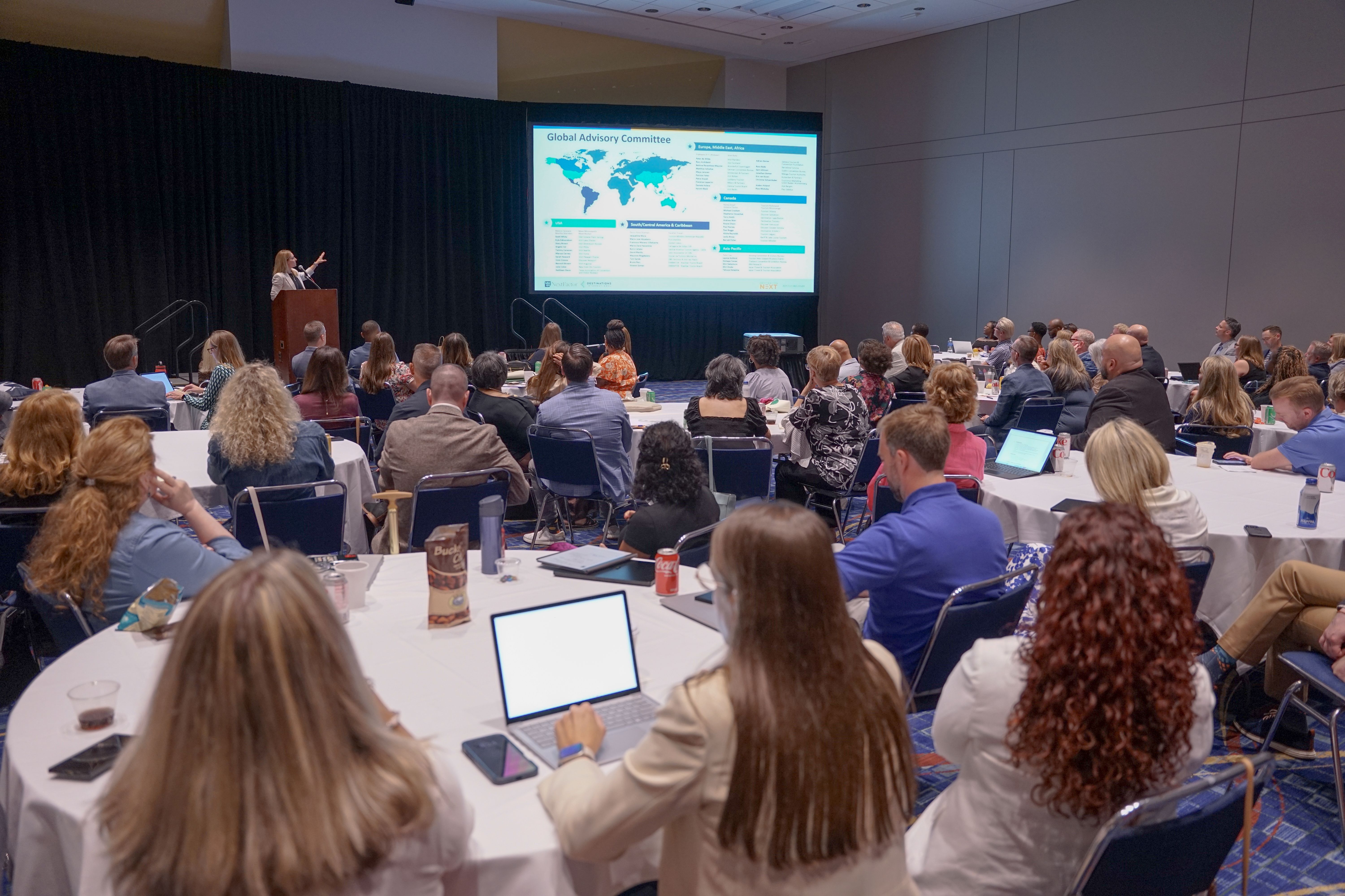 board of trustees sit at round tables and listen to a presentation