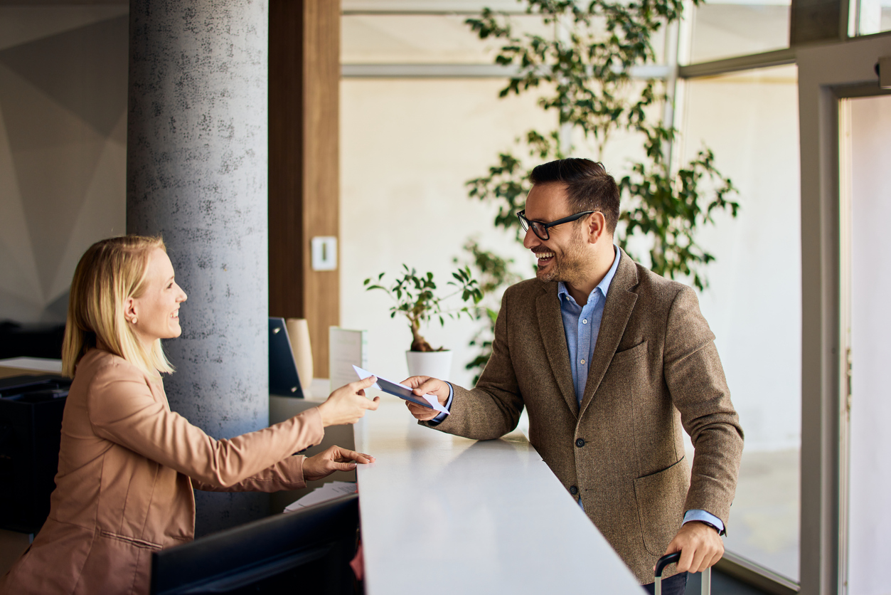 Businessman interacting with a receptionist while receiving a service at a reception desk.