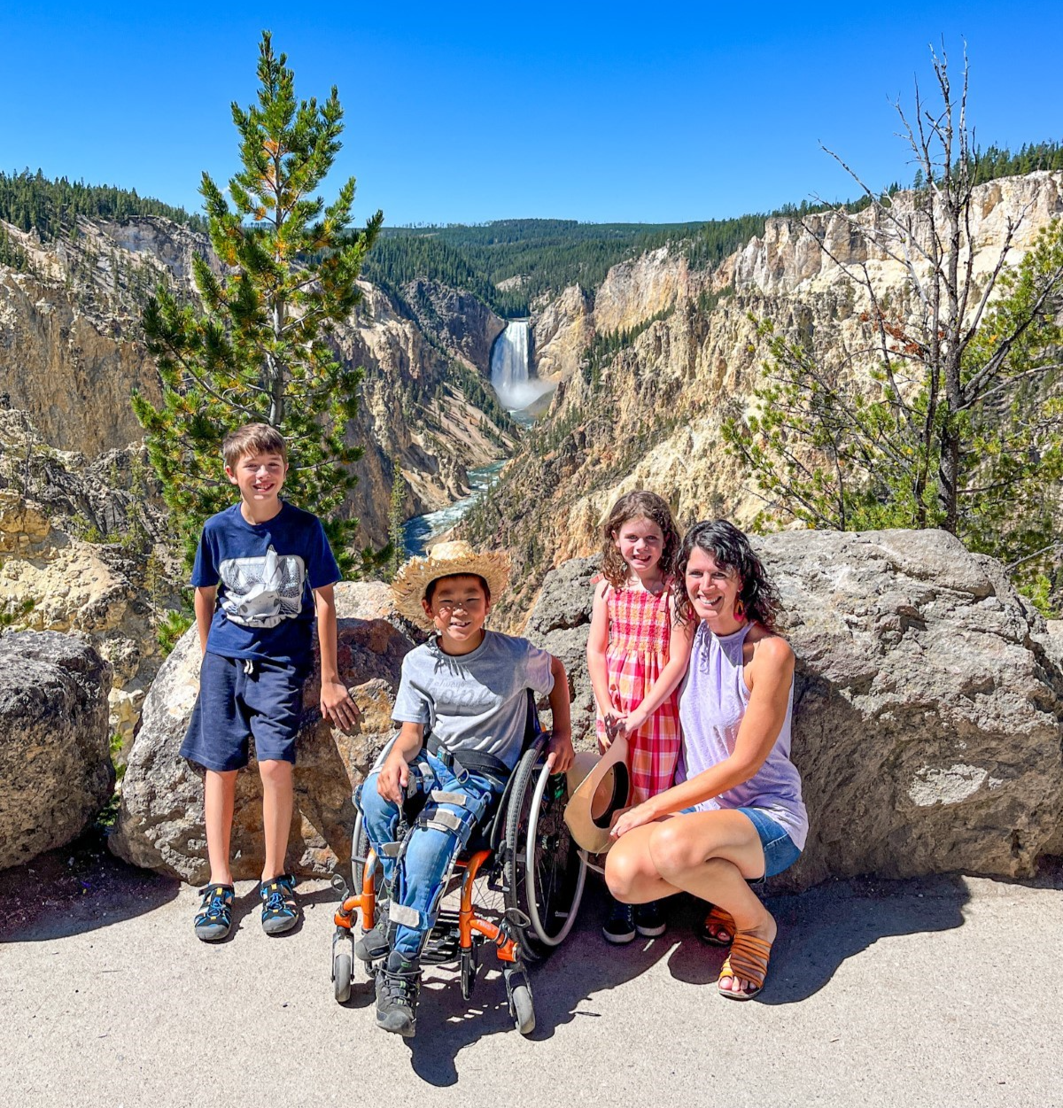 Jennifer Allen and her three children pose in a park with a beautiful view of a waterfall