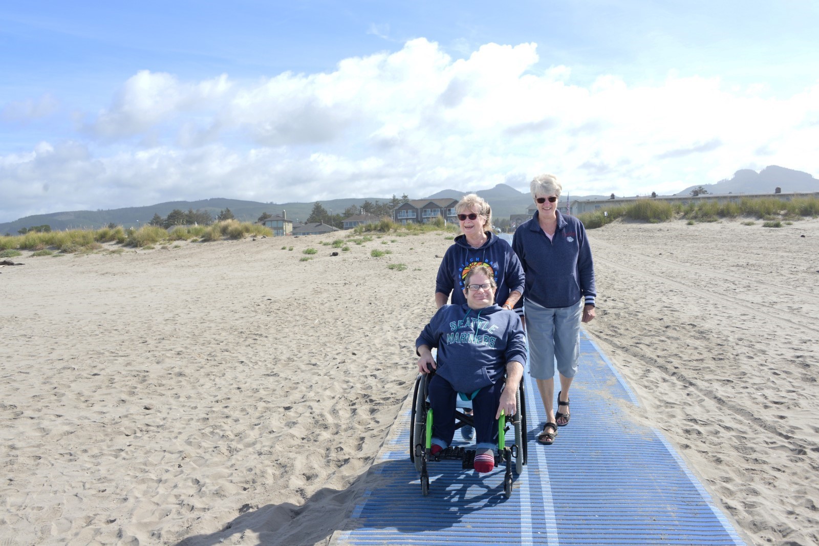 A family accessing the Mobi-Mat at Seaside, Oregon. The man in the wheelchair is Aaron Boggs, and he's with his mom Claudia and his aunt Jane.