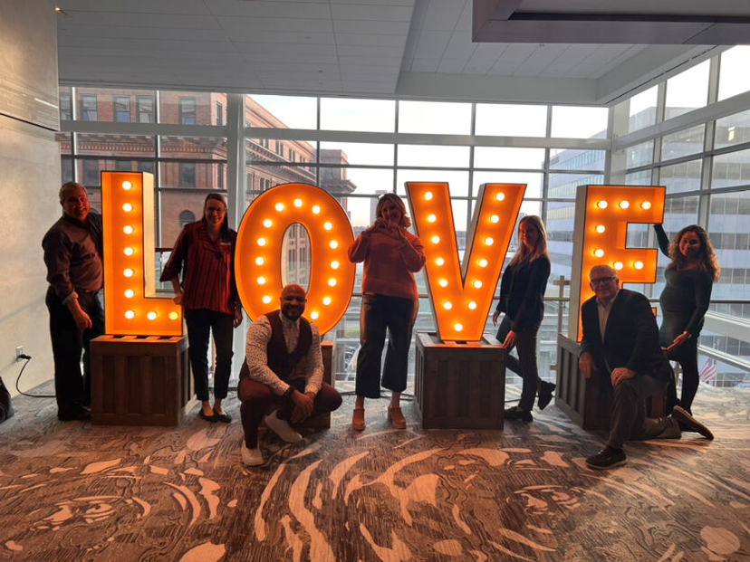 People around a light up love sign