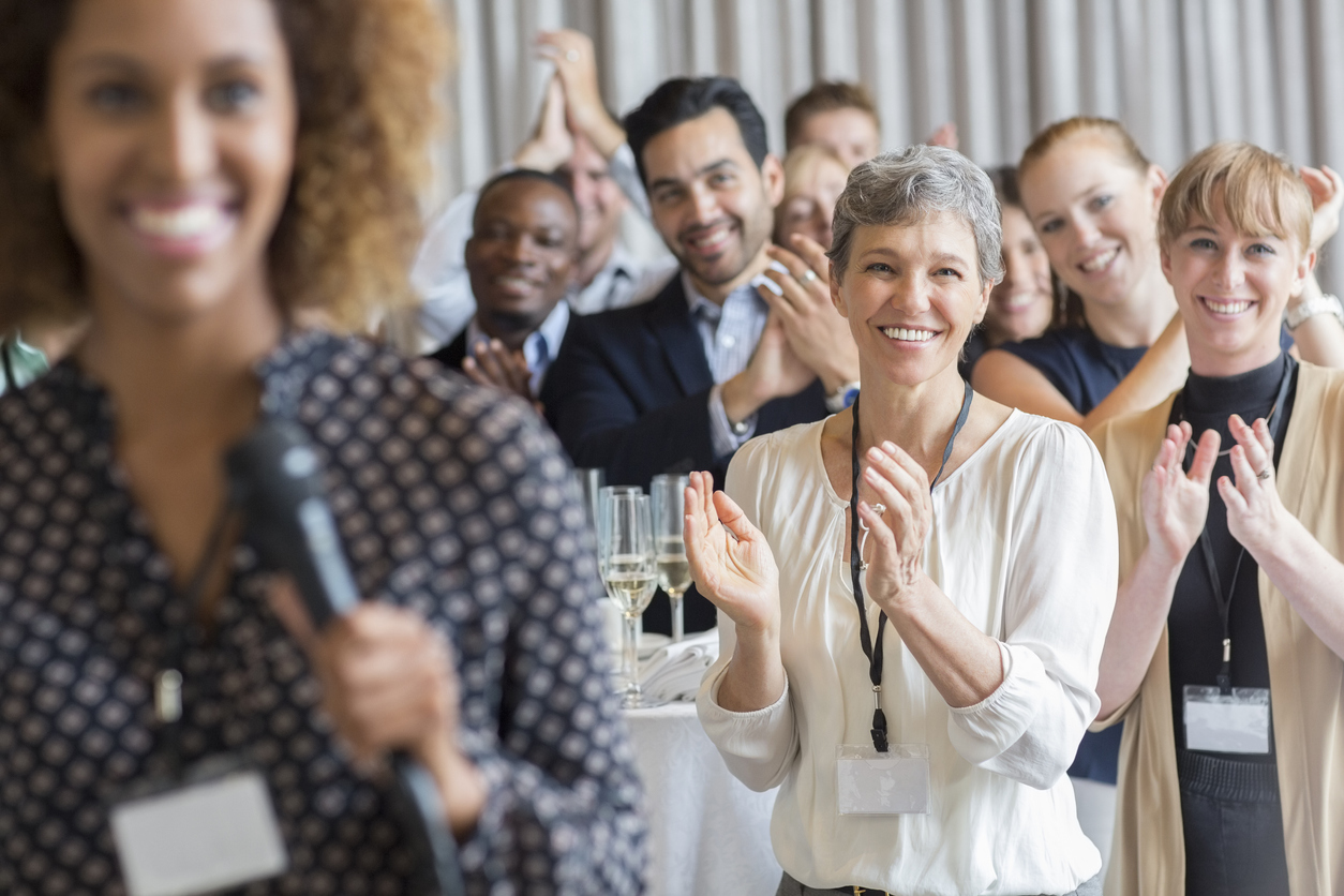 group of people standing, clapping and smiling in a business setting