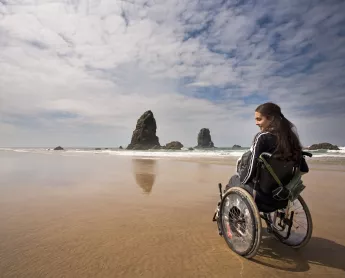 traveler in a wheelchair at haystack rock in cannon beach, oregon