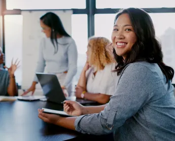 woman works on her computer while coworkers chat in the background