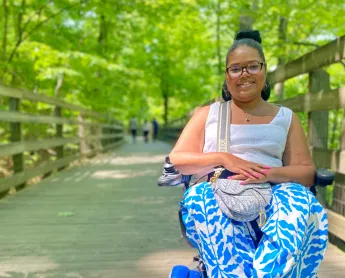 woman in motorized wheelchair smiling on a boardwalk