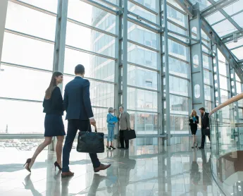 man and woman carrying briefcases walking through an office lobby