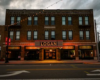 a building with its lights on. The sign says "LOGAN" in large letters