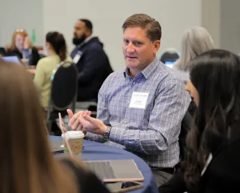 a man talks with his table-mates during a roundtable discussion
