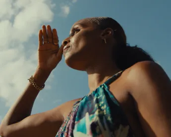woman with her hand in front of her face with the sky in the background