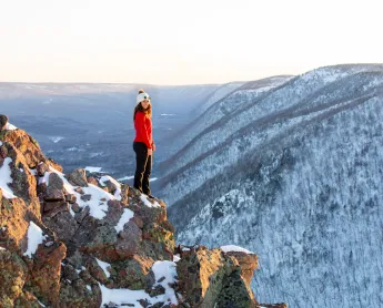 hiker looks around at the view of snow-covered mountains