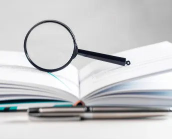 Magnifying lens over open paper book with pages.