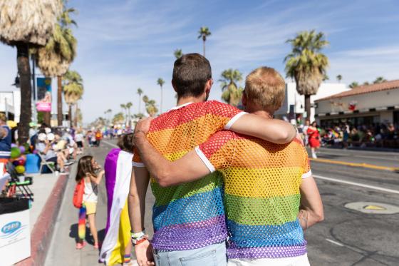 two people embrace while wearing Pride flag shirts
