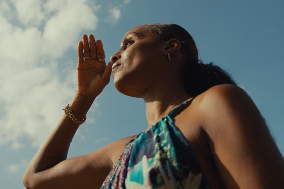 woman with her hand in front of her face with the sky in the background
