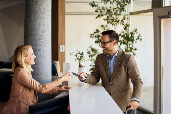 Businessman interacting with a receptionist while receiving a service at a reception desk.