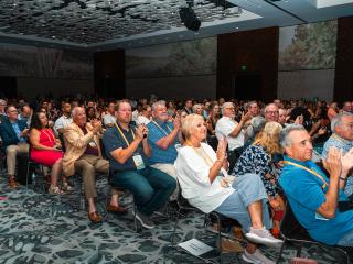 Crowd of attendees at Annual Convention clapping and looking towards the stage