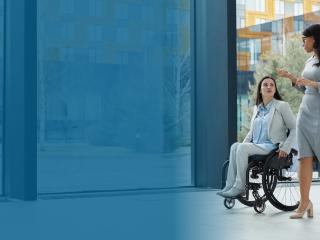 woman in wheelchair chats with coworker in an office setting