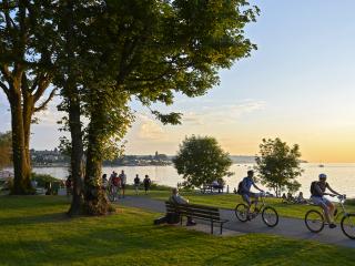 public park at sunset with people sitting on benches and riding bikes