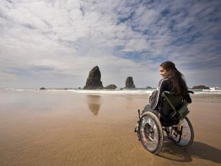 traveler in a wheelchair at haystack rock in cannon beach, oregon