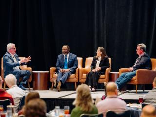 panel of speakers on stage at a conference