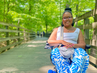woman in motorized wheelchair smiling on a boardwalk