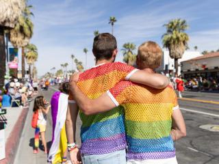 two people embrace while wearing Pride flag shirts