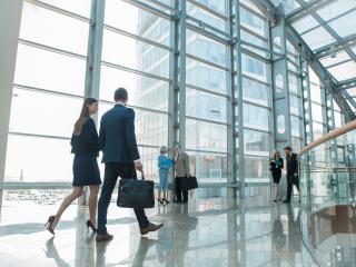Two coworkers converse while walking through a lobby of an office building