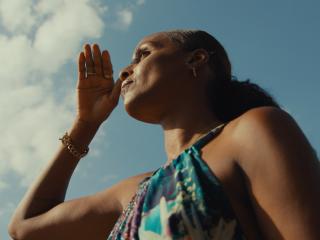 woman with her hand in front of her face with the sky in the background