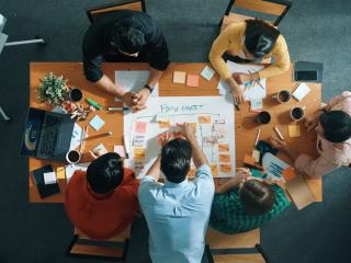 aerial view of a table where a group of coworkers collaborate on a chart using sticky notes
