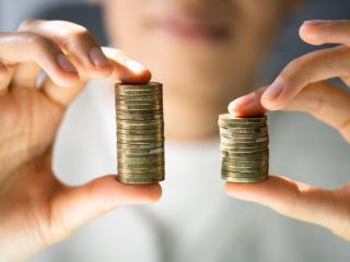 woman holding two stacks of coins comparing them