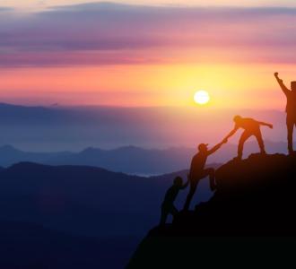 People reaching top of mountain at sun rise