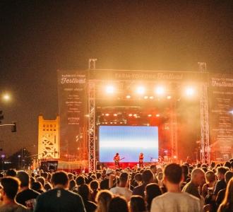 festival with a crowd of people facing a stage at night
