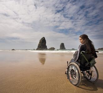 traveler in a wheelchair at haystack rock in cannon beach, oregon
