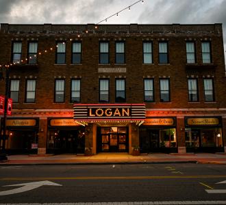 a building with its lights on. The sign says "LOGAN" in large letters