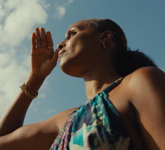 woman with her hand in front of her face with the sky in the background