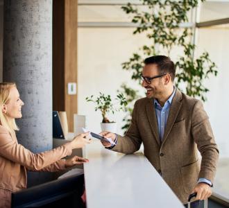 Businessman interacting with a receptionist while receiving a service at a reception desk.